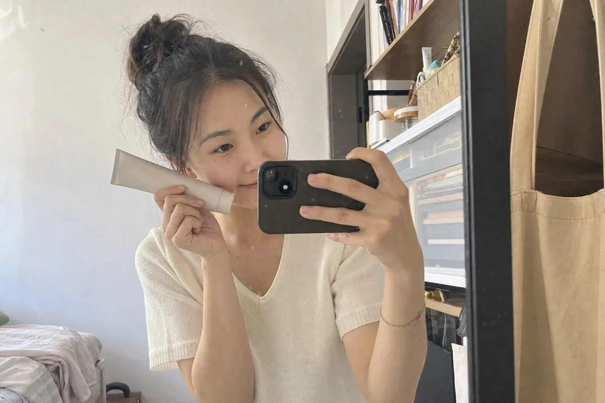 年轻女生在卧室镜子前用手机自拍分享日常使用的产品